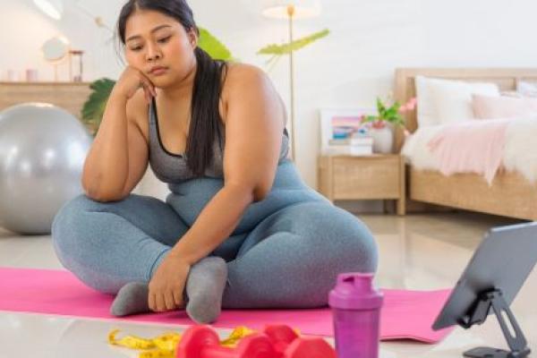 A woman sitting on an exercise mat and does not want to exercise.
