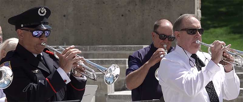 Photo of Dr. Bunty Shah playing the bugle along with two other participants.