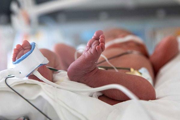 Newborn neonatal baby asleep in hospital infant warmer bed.