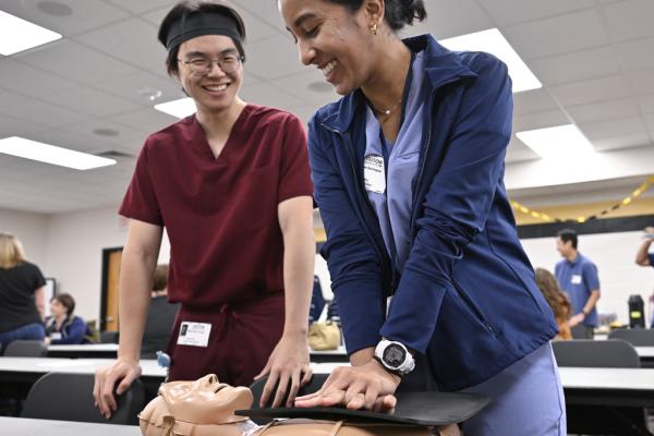 Two students practice CPR on a dummy