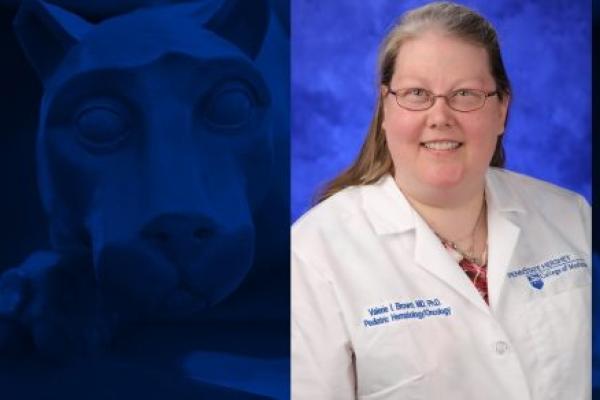 A photo of a women smiling for a headshot. She is wearing a white doctor's coat.