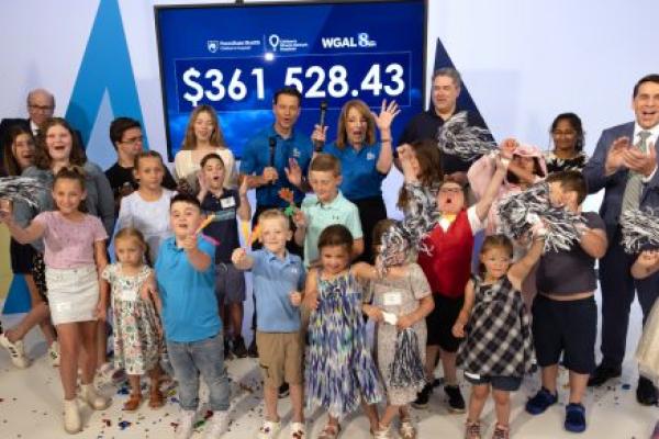 Several people stand in front of an electronic display with the amount $361,528.43 on it.