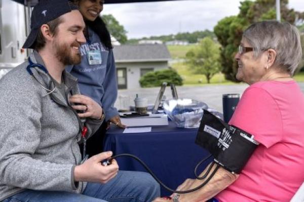 A medical student gives a woman a blood pressure reading.