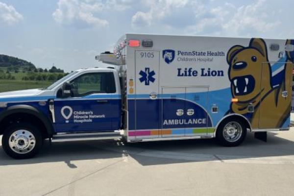 An ambulance bears the Children’s Miracle Network and Penn State Health logos and marks, as well as the likeness of a costumed Nittany Lion.