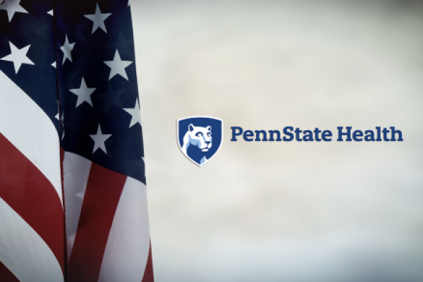 An American flag hangs down on the left, and to the right is the Penn State Health logo.