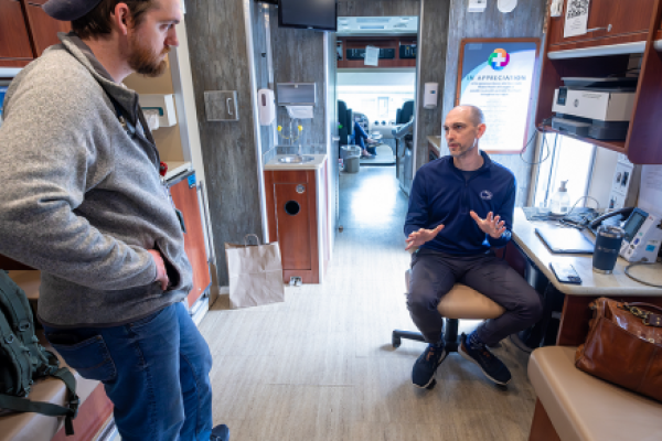 Two men talk inside a mobile medical clinic