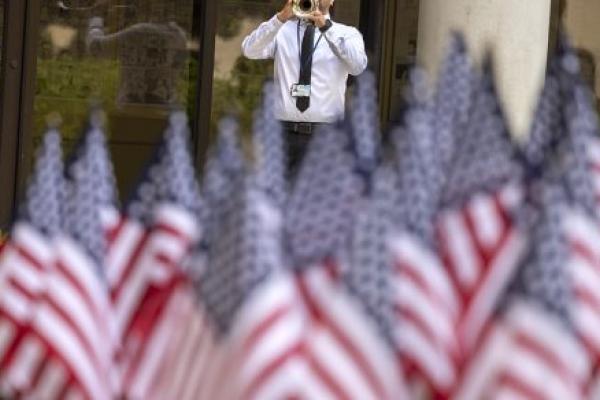 Man playing trumpet with a foreground that includes several U.S. flags.