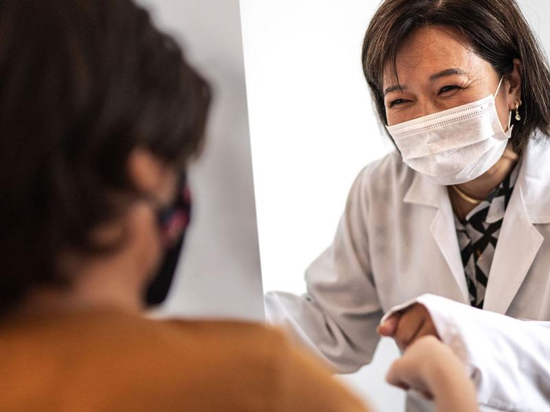 Female doctor with medical grade face mask is fit bumping and young child.