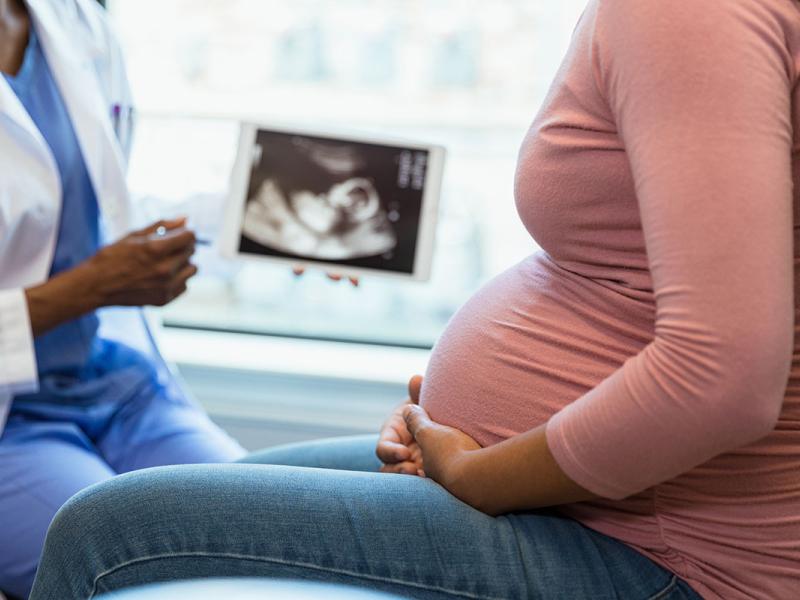 Pregnant woman at the doctor’s office looking at ultrasound pictures on the doctor’s laptop.